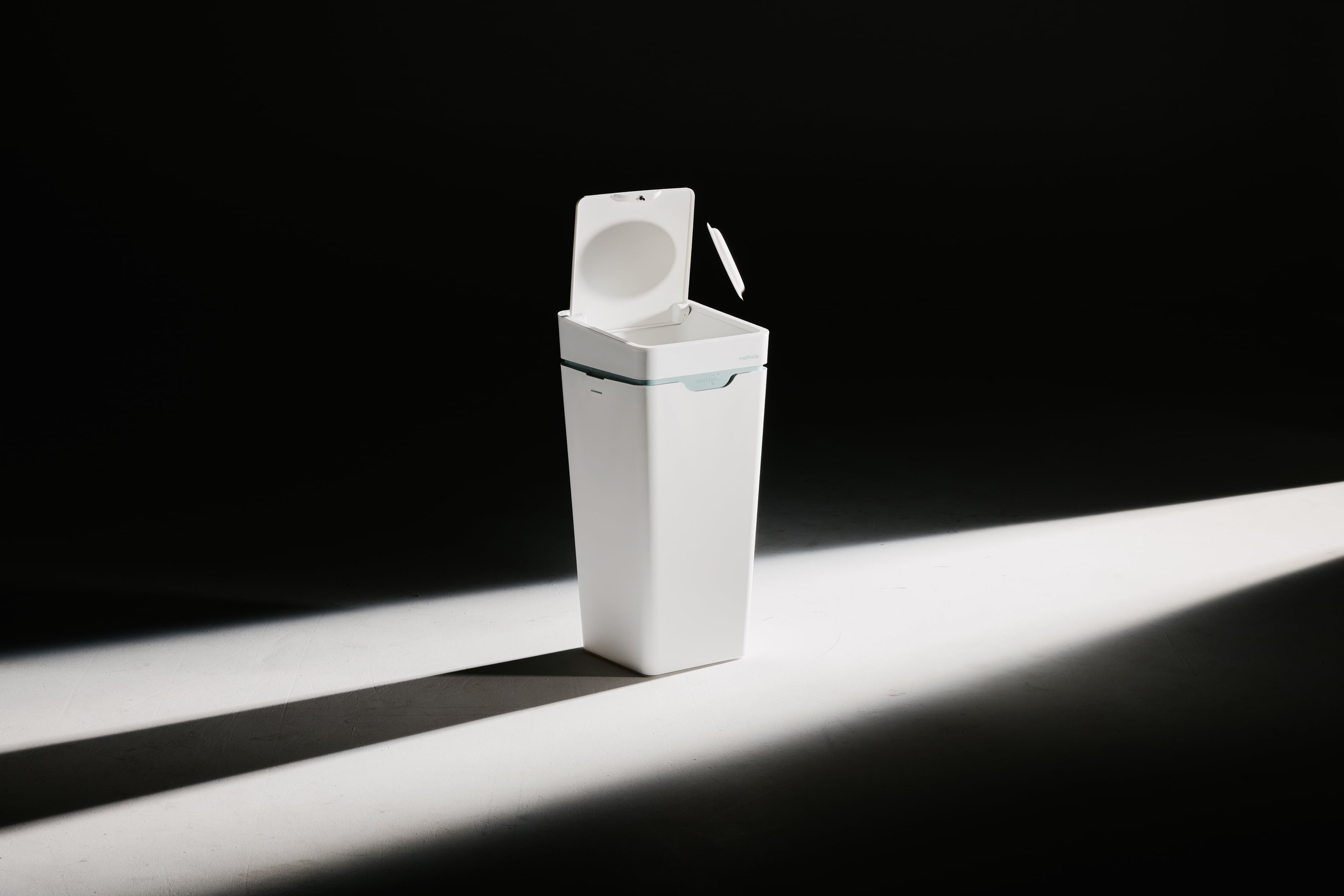 A white Mono bin with its lid open, in a beam of light